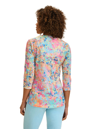 Woman wearing a colorful floral blouse with a beige background