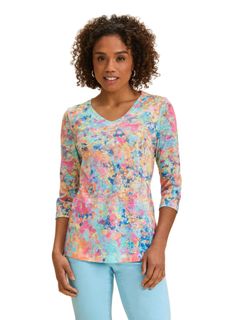 Woman wearing a colorful floral long-sleeve top against a beige background