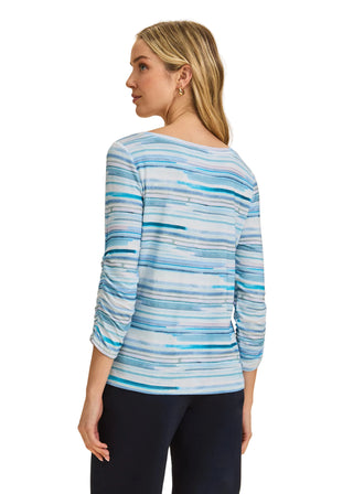 Woman wearing a blue striped long-sleeve top against a beige background