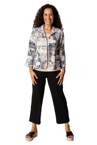 Woman wearing a patterned jacket and black pants against a plain background