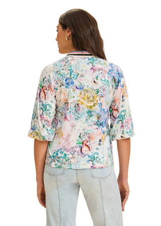 Woman wearing a colorful floral blouse against a beige background