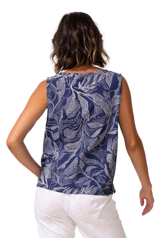Woman wearing a sleeveless top with a blue leaf pattern on a white background