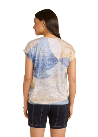 Woman wearing a sheer top with blue and white pattern on a beige background