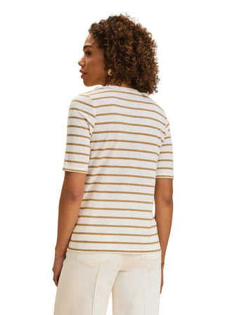 Woman wearing a striped shirt and white pants against a beige background