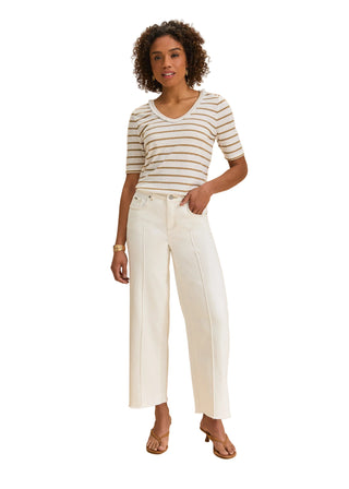 Woman wearing a striped shirt and white pants on a beige background