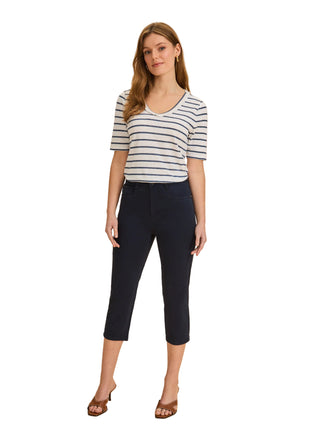 Woman wearing a striped shirt and navy capri pants on a beige background