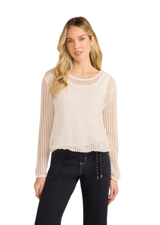 Woman wearing a white ribbed sweater and dark pants against a beige background