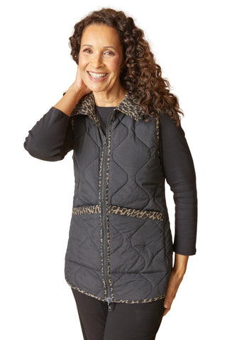 Woman wearing a dark quilted jacket with patterned trim on a beige background