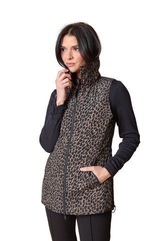 Woman wearing a leopard print vest over a black long-sleeve shirt on a beige background