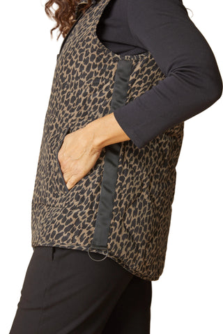 Person wearing a leopard print vest over a black long-sleeve shirt on a beige background
