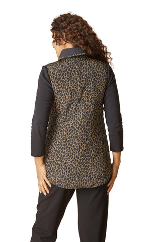 Person wearing a leopard print vest over a black shirt on a beige background