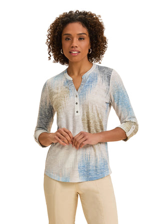 Woman wearing a patterned shirt with rolled-up sleeves against a beige background