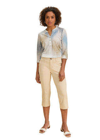 Woman wearing a light blue and white patterned shirt with beige pants on a beige background