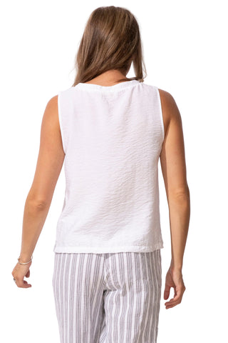 Woman wearing a white sleeveless top and striped pants on a white background