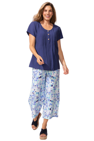 Woman wearing a blue top and patterned pants on a white background