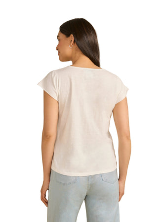 Woman wearing a white t-shirt and light blue jeans against a beige background