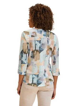 Woman wearing a colorful abstract patterned blouse against a beige background