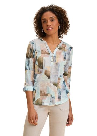 Woman wearing a patterned blouse against a beige background