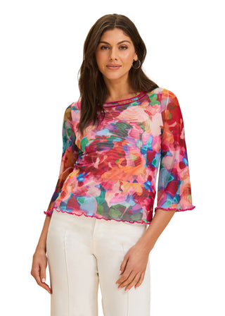 Woman wearing a colorful floral blouse against a beige background