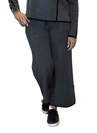 Person wearing a gray outfit with wide-leg pants in front of a branded backdrop