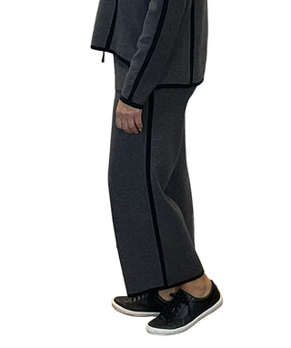 Person wearing a gray suit with black trim against a white wall with branding.
