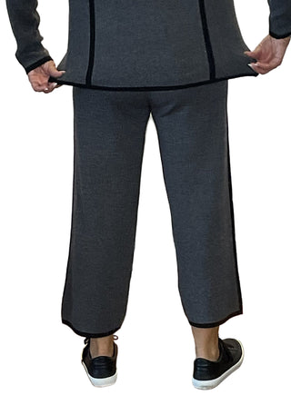 Person wearing a gray outfit with wide-leg pants in front of a white wall with text.