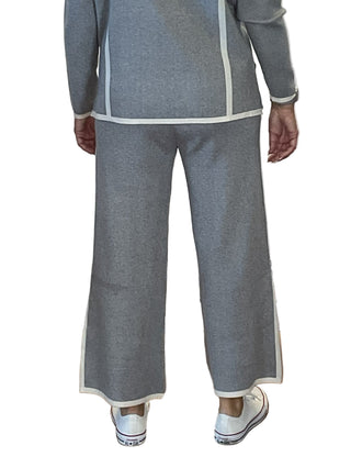 Person wearing a gray outfit with white trim on a wooden floor.