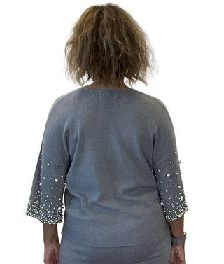 Person wearing a blue dress with beaded sleeves against a white background