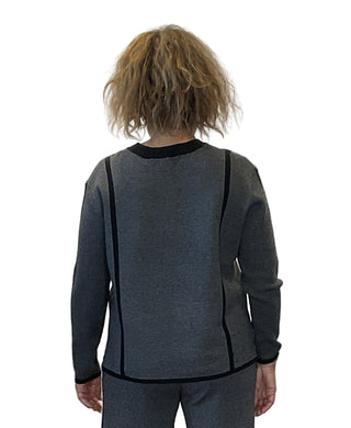 Person wearing a gray sweater with black trim against a white background