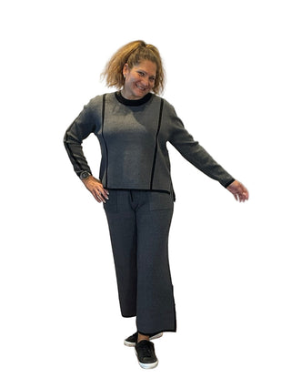 Woman posing in a gray outfit against a branded backdrop
