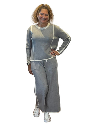 Woman in gray tracksuit posing in front of a branded backdrop