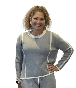 Woman wearing a gray and white outfit against a plain background