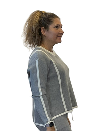 Woman wearing a gray and white outfit against a plain background