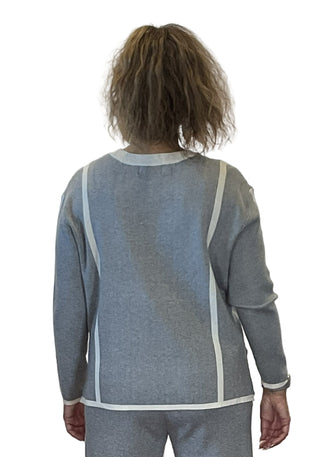 Person wearing a gray sweater with a white collar against a plain background