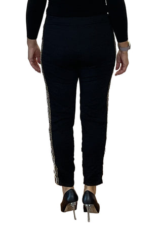 Person wearing black pants with white trim standing against a plain background