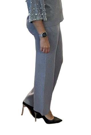 Person wearing a gray outfit with black high heels in front of a white backdrop with text.
