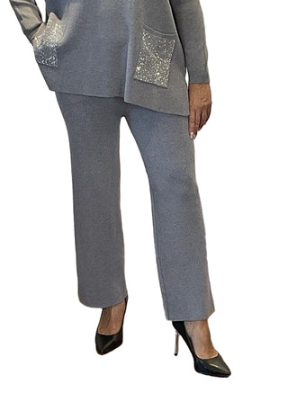 Person wearing a gray suit with sequin pockets on a wooden floor.