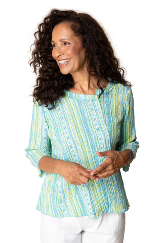Woman wearing a light blue and green striped shirt against a beige background