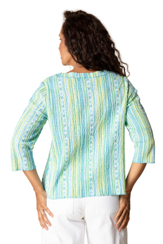 Woman wearing a light blue and green striped shirt against a beige background