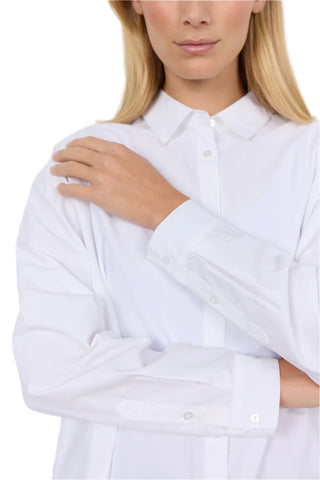 Person wearing a white shirt against a plain background