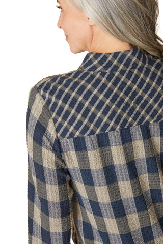 Person wearing a blue and beige checkered shirt against a beige background