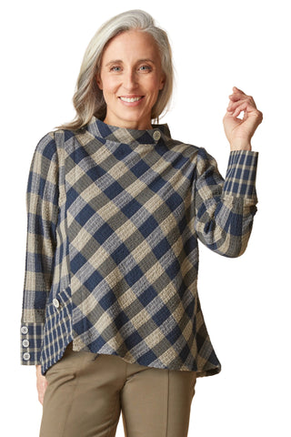 Woman wearing a blue and beige checkered shirt against a beige background