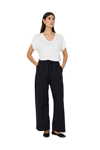 Woman wearing a white top and black pants against a white background