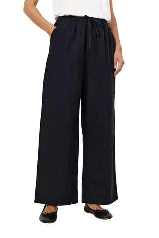 Person wearing black wide-leg pants with a white top on a plain background