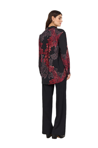 Woman wearing a black and red patterned blouse with black pants against a white background