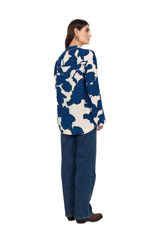 Person wearing a blue and white patterned shirt and blue jeans against a white background