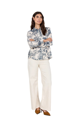 Woman wearing a floral blouse and white pants against a white background