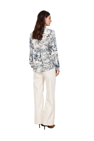 Woman wearing a floral blouse and white pants against a white background