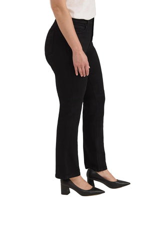 A model wearing black high-waisted straight-leg trousers, paired with a white top and black pointed-toe heels, shown from the waist down against a light beige studio background.
