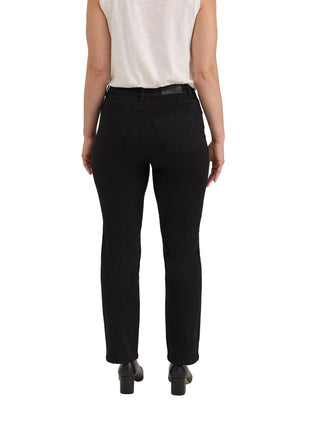 Rear view of a model wearing black high-waisted straight-leg jeans, a white sleeveless top, and black shoes against a light gray studio background.